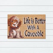 Doormat with a cavoodle illustration and text 'Life is Better With A Cavoodle' on a wooden background.