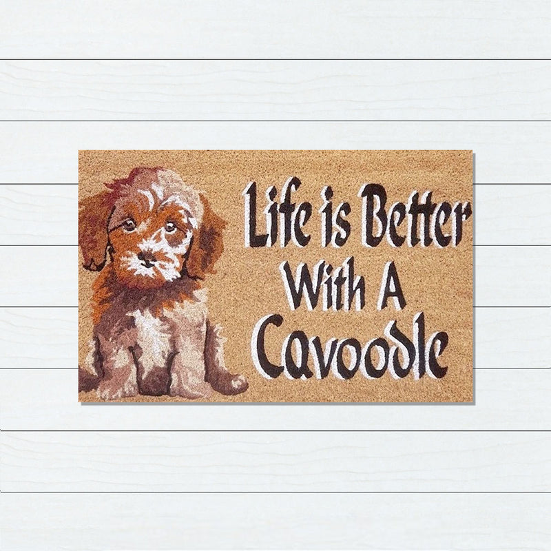 Doormat with a cavoodle illustration and text 'Life is Better With A Cavoodle' on a wooden background.